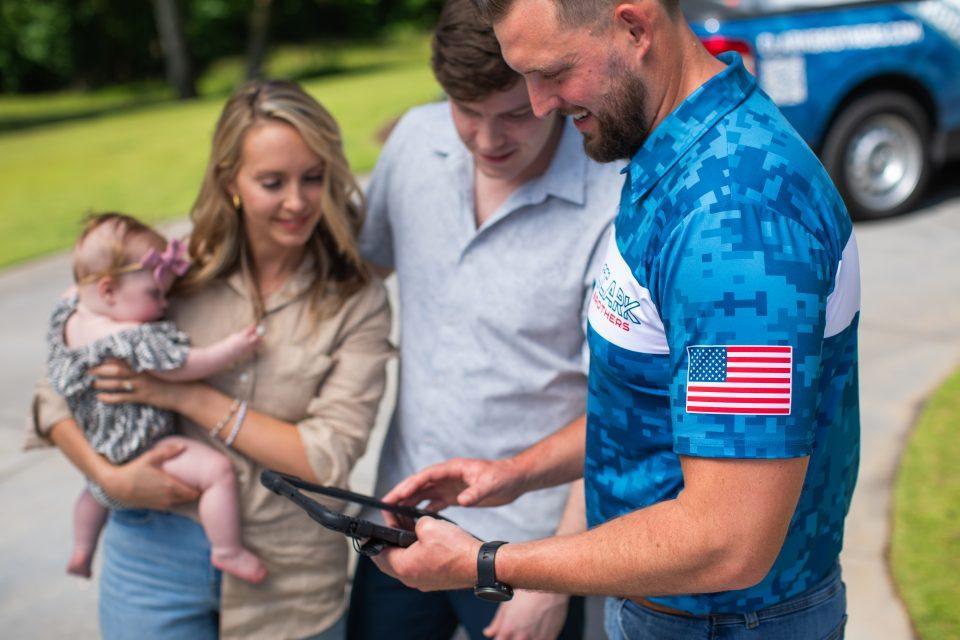 Clark Brothers Roofing contractor Micah Clark explaining RCV vs ACV home insurance coverage options to a family after storm damage.